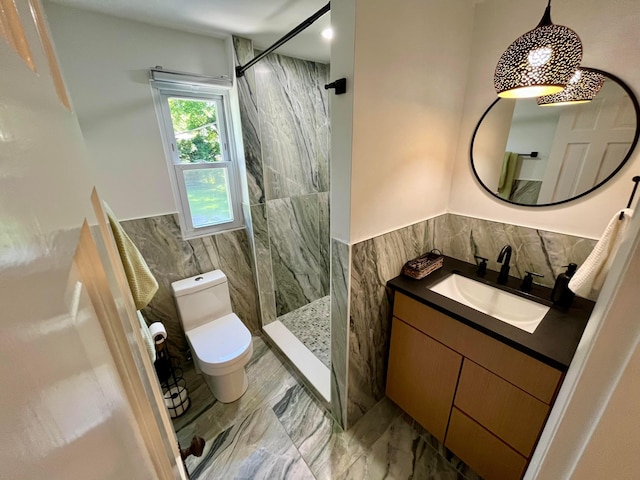 bathroom featuring vanity, toilet, tile walls, and a tile shower