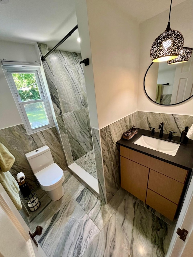 bathroom with vanity, tile walls, toilet, and tiled shower