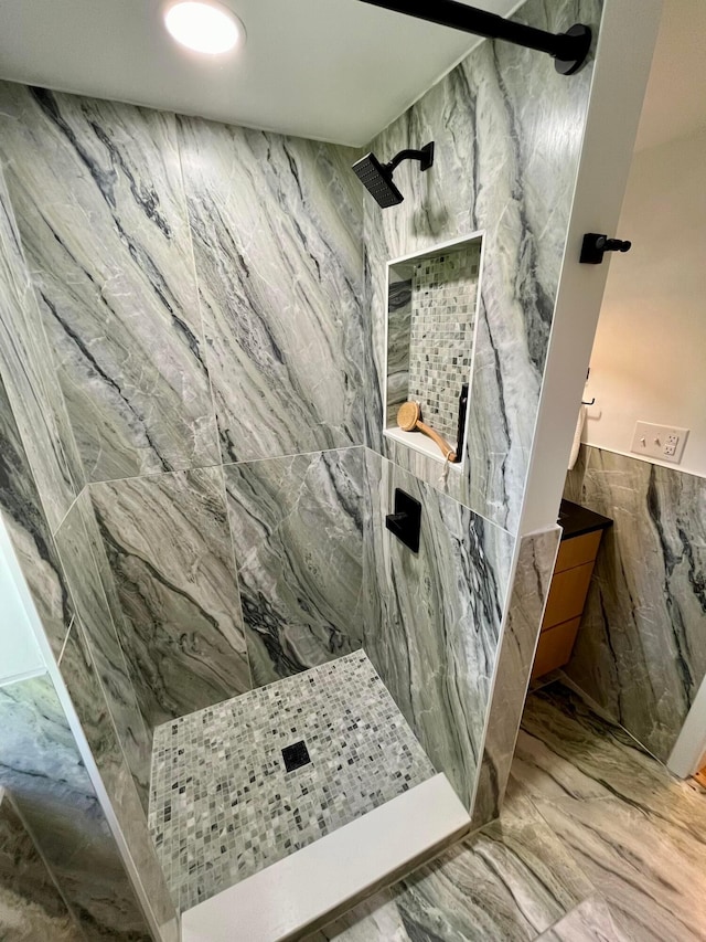 bathroom with a tile shower and tile walls