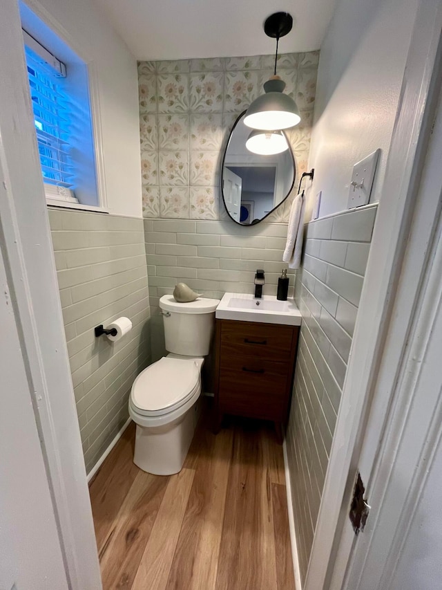 bathroom featuring vanity, hardwood / wood-style floors, tile walls, and toilet