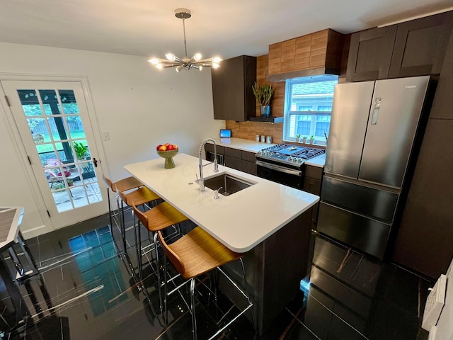 kitchen featuring sink, a breakfast bar, a kitchen island with sink, stainless steel appliances, and decorative light fixtures