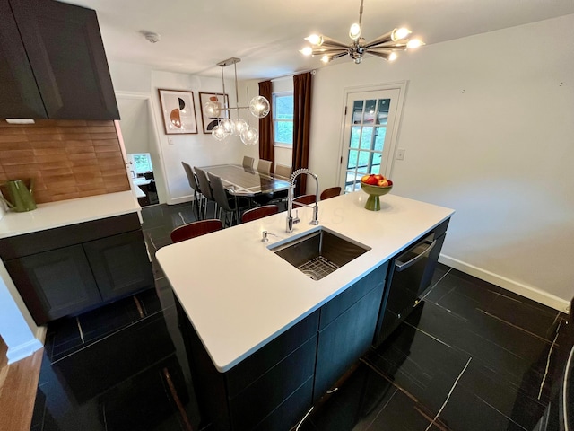 kitchen with a kitchen island with sink, sink, black dishwasher, and a chandelier