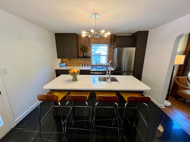 kitchen with decorative backsplash, stainless steel fridge, a kitchen breakfast bar, and a center island with sink