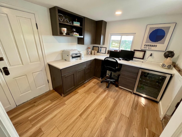 office area with light hardwood / wood-style floors and beverage cooler