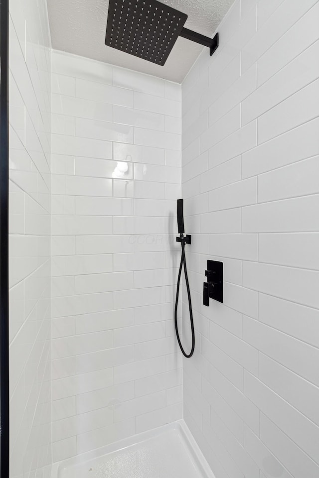 room details with a textured ceiling and tiled shower