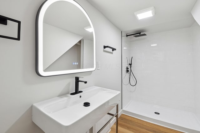 bathroom with sink, hardwood / wood-style floors, and a tile shower