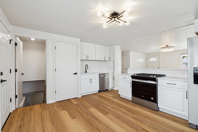 kitchen featuring appliances with stainless steel finishes, a textured ceiling, white cabinets, and light hardwood / wood-style floors