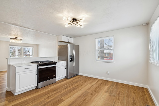 kitchen featuring white cabinetry, appliances with stainless steel finishes, light hardwood / wood-style flooring, and a textured ceiling