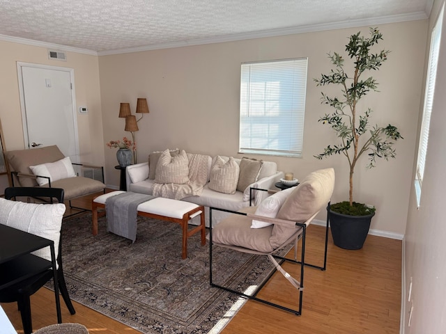 living room featuring visible vents, a textured ceiling, crown molding, and light wood-style floors