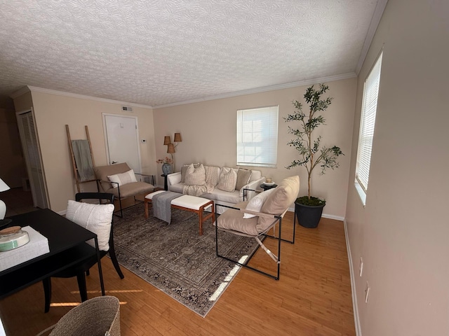 living room featuring crown molding, a healthy amount of sunlight, light wood-type flooring, and visible vents