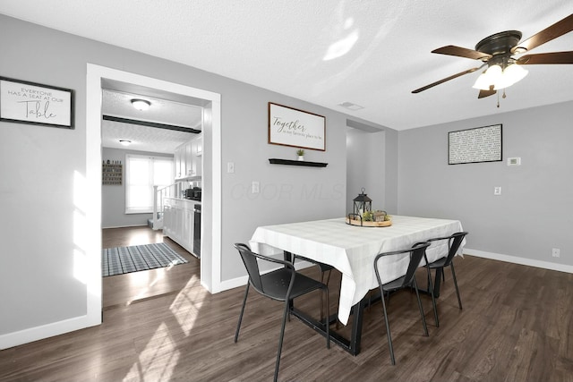 dining area featuring ceiling fan, dark wood-type flooring, and a textured ceiling