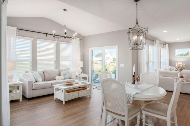 dining space featuring an inviting chandelier, vaulted ceiling, and light wood-type flooring