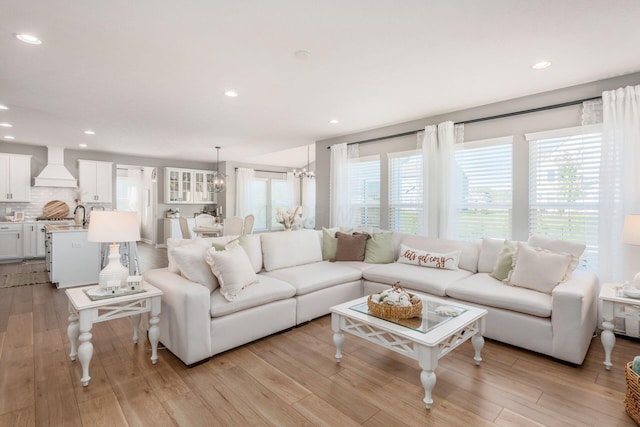 living room featuring sink, a wealth of natural light, a notable chandelier, and light wood-type flooring