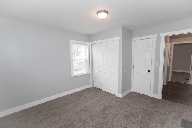 unfurnished bedroom featuring dark carpet and a closet