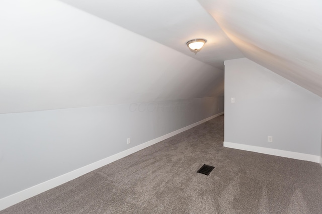 additional living space with vaulted ceiling and dark colored carpet