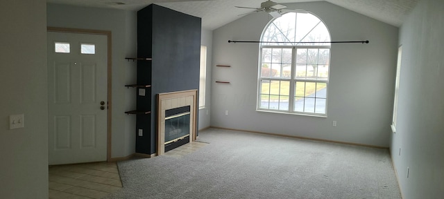 foyer entrance featuring a tiled fireplace, light colored carpet, lofted ceiling, and ceiling fan