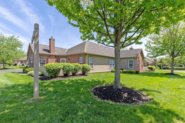 view of home's exterior featuring a yard, brick siding, and a chimney
