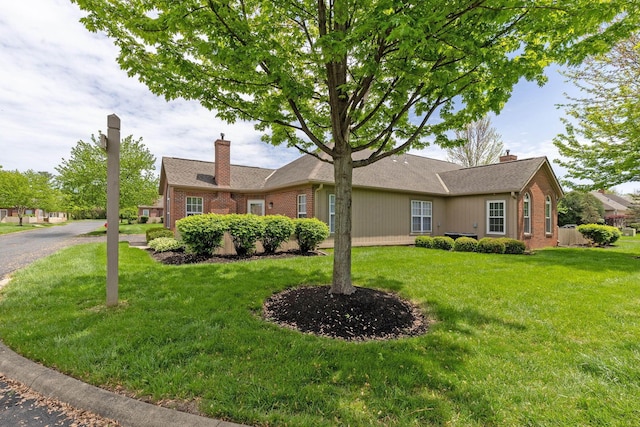 view of front facade with brick siding, a front lawn, and a chimney
