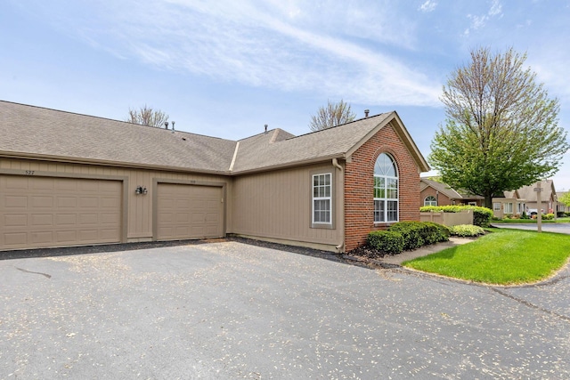 view of side of property with roof with shingles, a garage, and brick siding