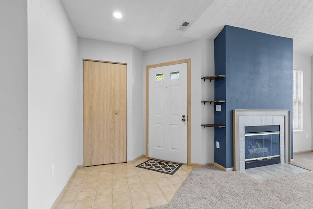 tiled foyer featuring visible vents, baseboards, plenty of natural light, and a tiled fireplace