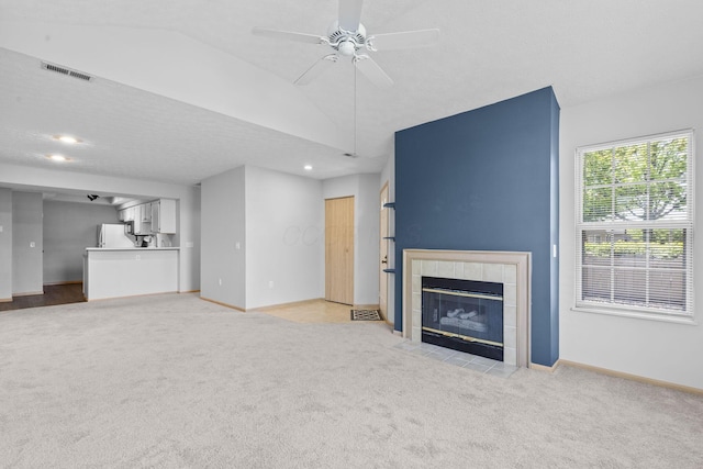 unfurnished living room with light carpet, a fireplace, a ceiling fan, baseboards, and visible vents
