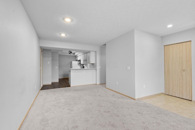 unfurnished living room featuring baseboards, recessed lighting, and light colored carpet
