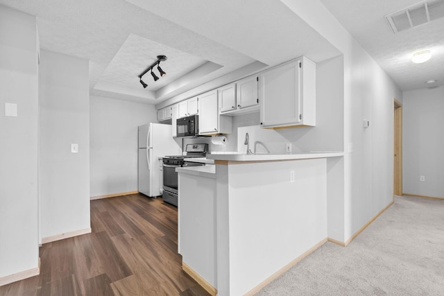 kitchen featuring black microwave, stainless steel gas range oven, a raised ceiling, a textured ceiling, and visible vents