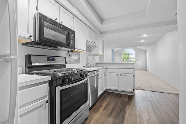 kitchen featuring a sink, light countertops, a peninsula, stainless steel appliances, and white cabinetry