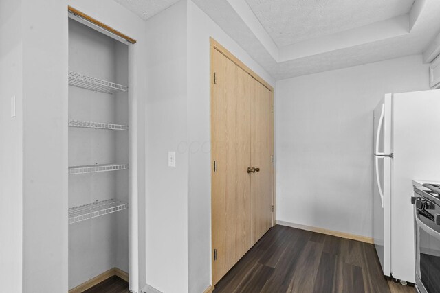 interior space with stainless steel stove, a textured ceiling, baseboards, and dark wood-type flooring