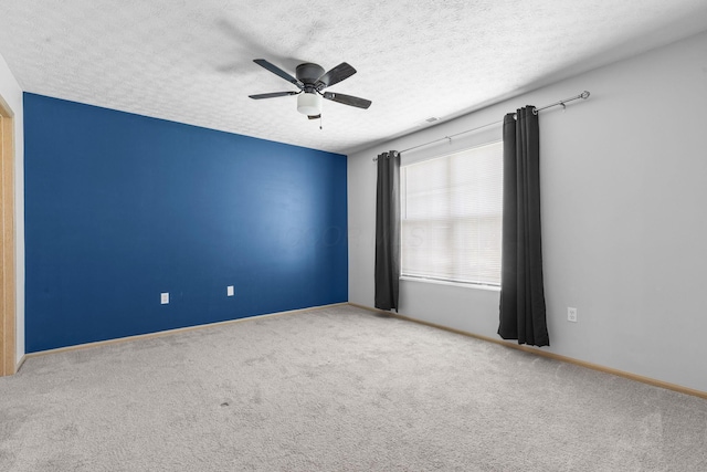 carpeted spare room with baseboards, a ceiling fan, and a textured ceiling