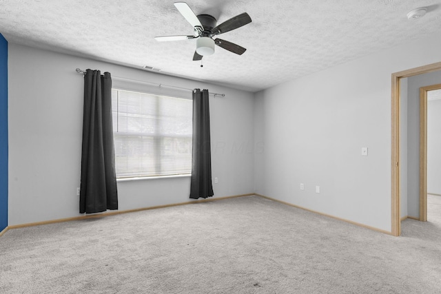 carpeted empty room with baseboards, a textured ceiling, visible vents, and ceiling fan