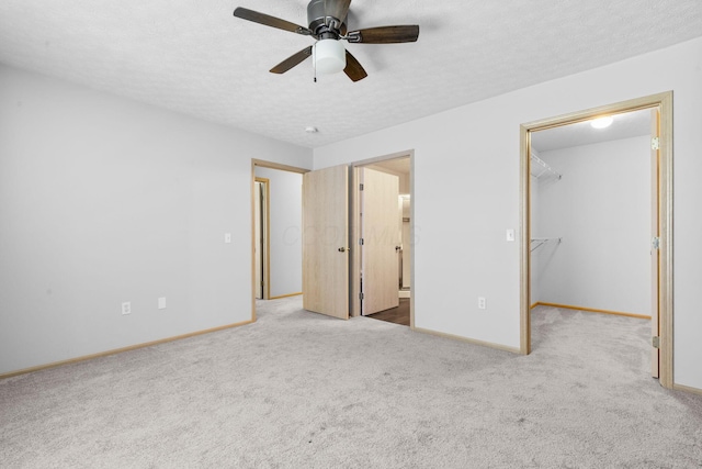unfurnished bedroom featuring connected bathroom, baseboards, a walk in closet, and carpet