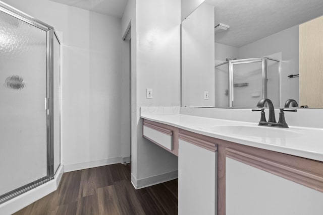 full bathroom with vanity, baseboards, wood finished floors, and a stall shower