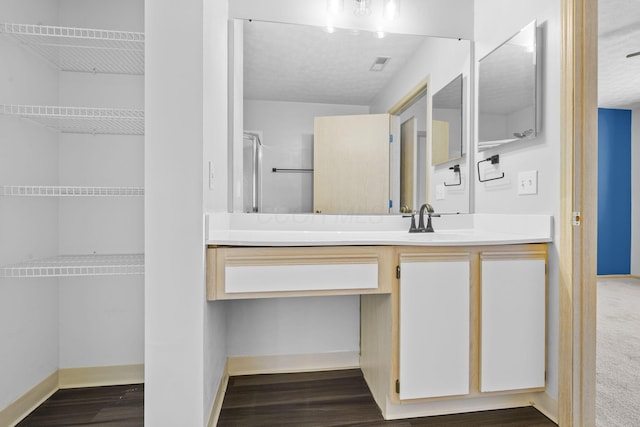 bathroom featuring baseboards, vanity, wood finished floors, and visible vents