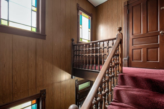 stairs featuring a healthy amount of sunlight and wood walls