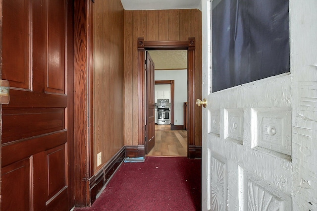 corridor with wooden walls and dark colored carpet