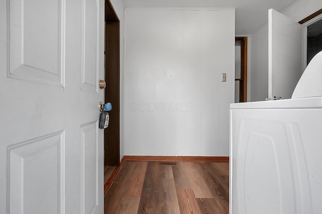 corridor with washer / dryer and dark wood-type flooring