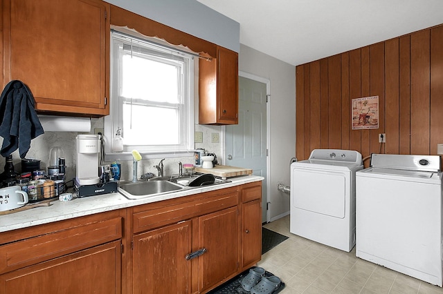 clothes washing area featuring separate washer and dryer, sink, and wooden walls