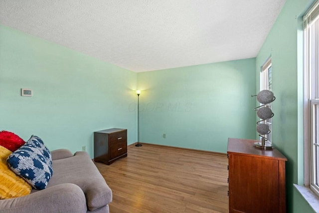 sitting room featuring a textured ceiling, baseboards, and wood finished floors