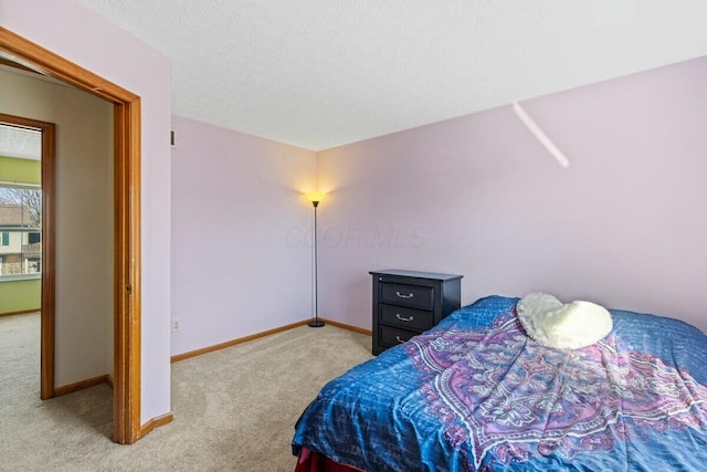 bedroom featuring light colored carpet, a textured ceiling, and baseboards