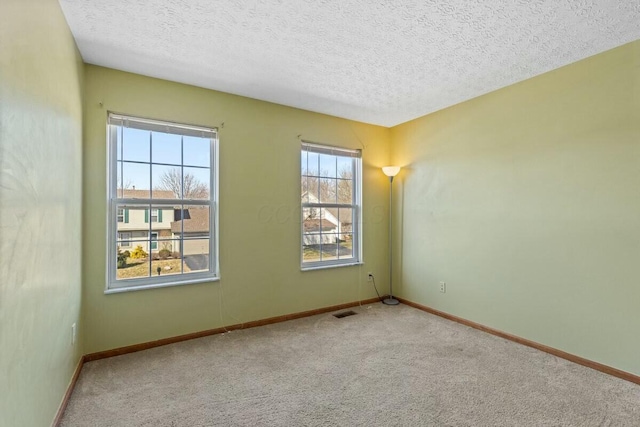 carpeted spare room with visible vents, a textured ceiling, and baseboards