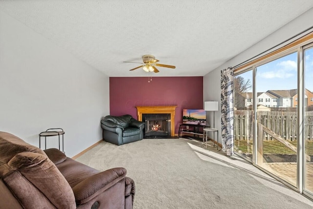 carpeted living area with a textured ceiling, a fireplace with flush hearth, a ceiling fan, and baseboards