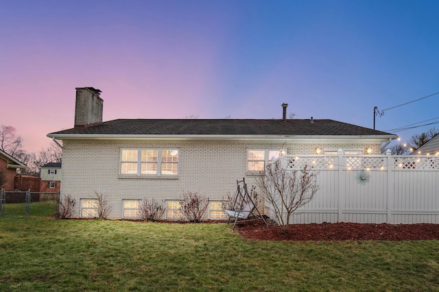 property exterior at dusk featuring a lawn