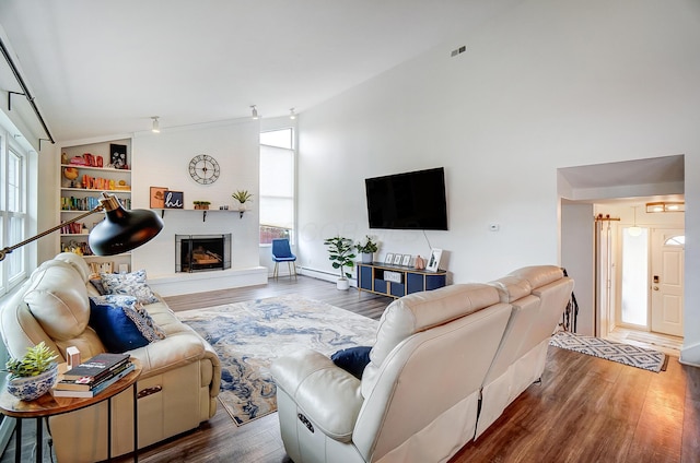 living room featuring wood-type flooring, built in features, and high vaulted ceiling