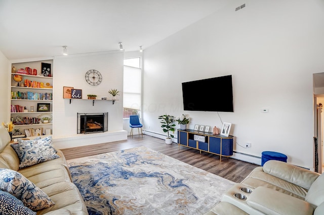 living room with hardwood / wood-style flooring, a baseboard radiator, high vaulted ceiling, and a fireplace