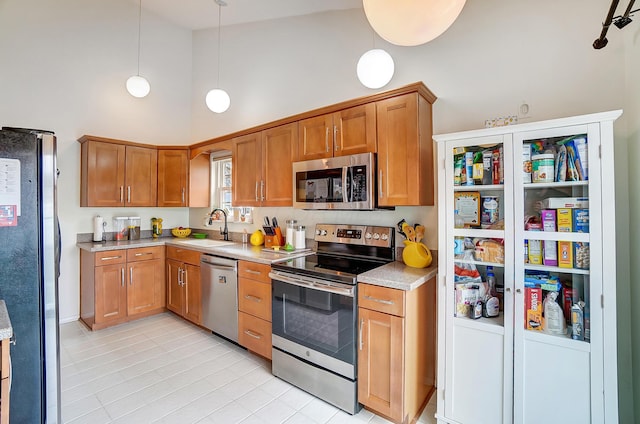 kitchen with pendant lighting, high vaulted ceiling, stainless steel appliances, and sink