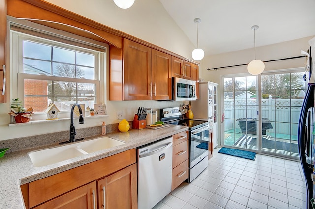 kitchen with lofted ceiling, sink, light stone counters, pendant lighting, and stainless steel appliances