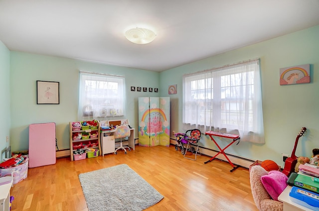 game room featuring a healthy amount of sunlight, light hardwood / wood-style floors, and a baseboard heating unit