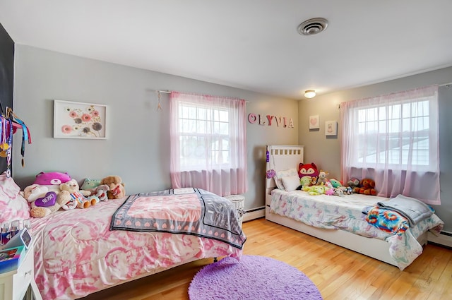 bedroom featuring hardwood / wood-style floors and a baseboard heating unit