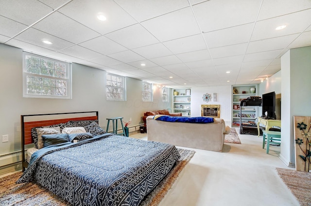 carpeted bedroom with a baseboard heating unit and a drop ceiling